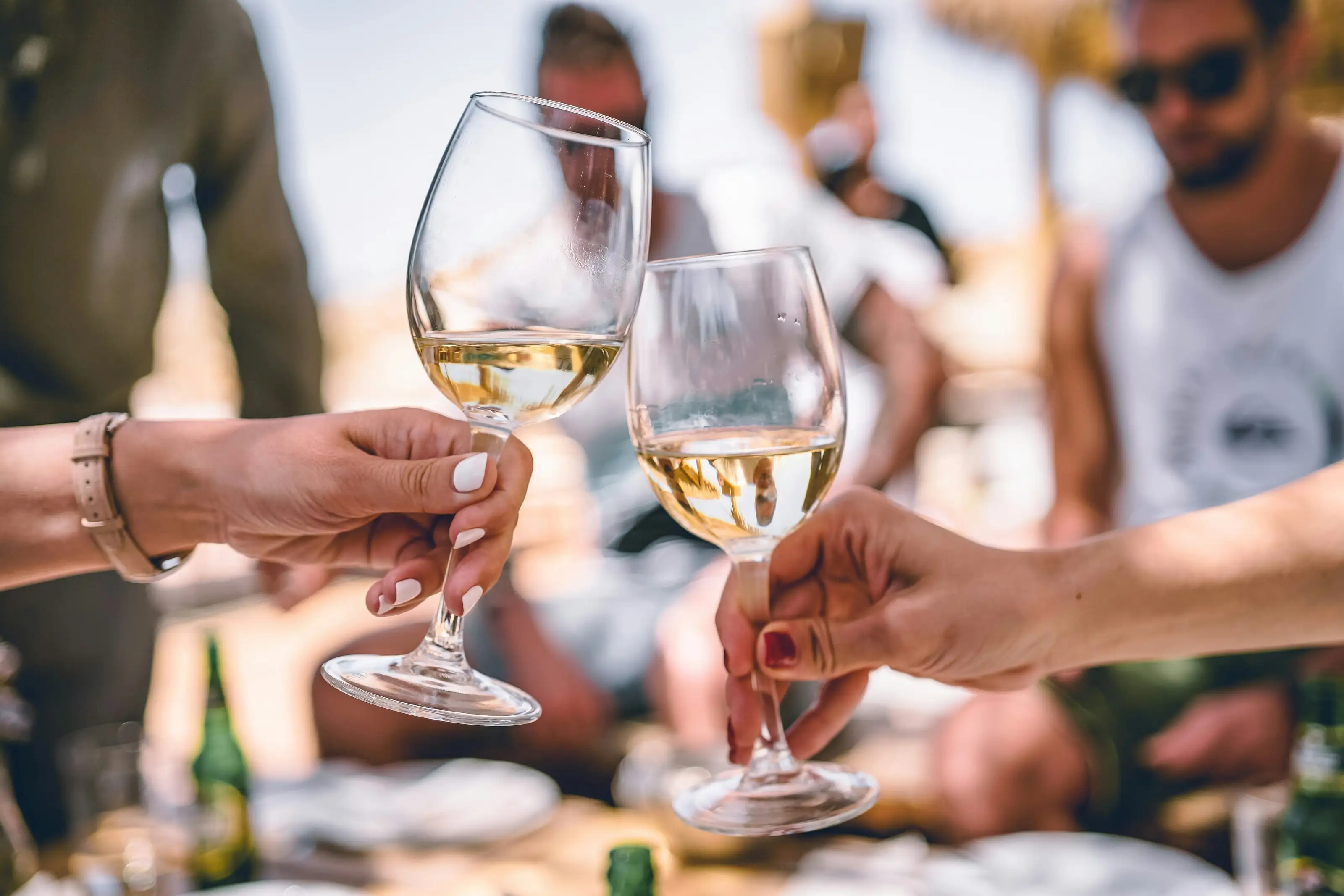 Gläser mit Weißwein stoßen bei einer Feier im Freien an